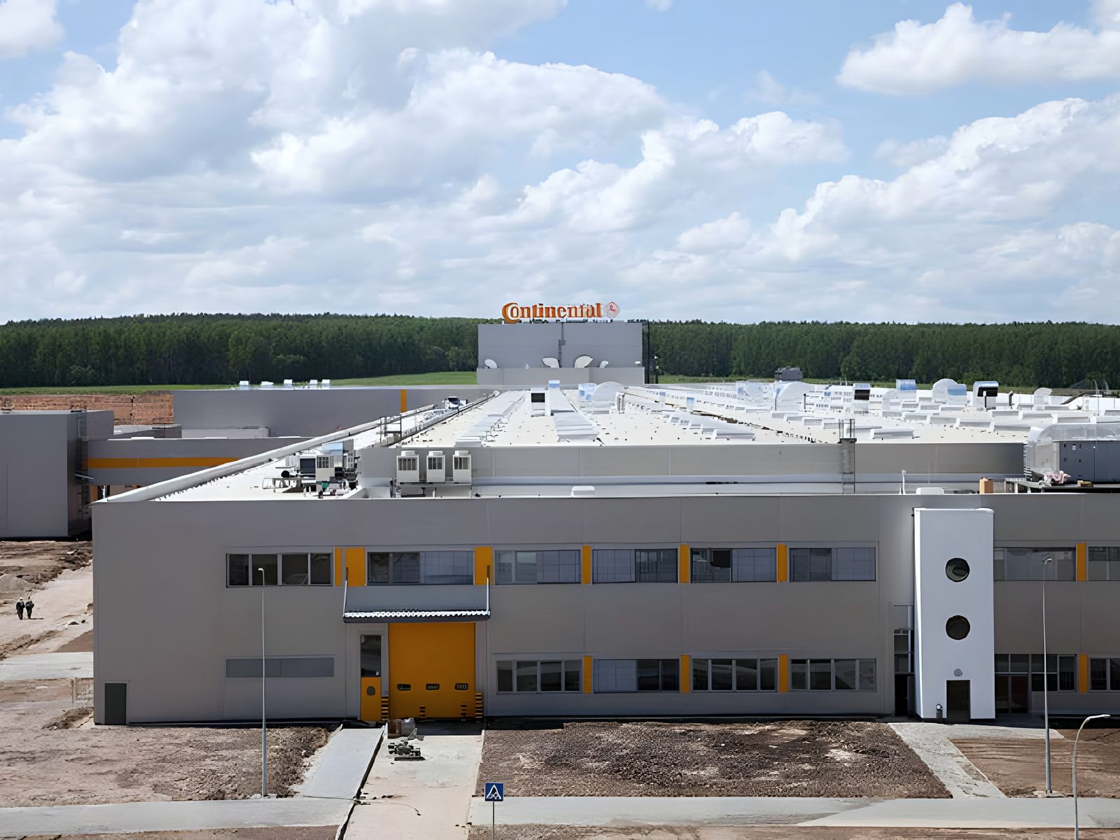Completed plant with branded roof sign under a cumulus sky