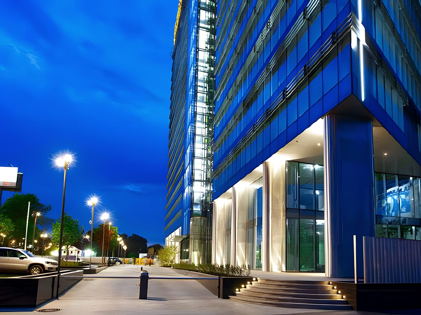 Night street-level view of glass office tower and lit entrance