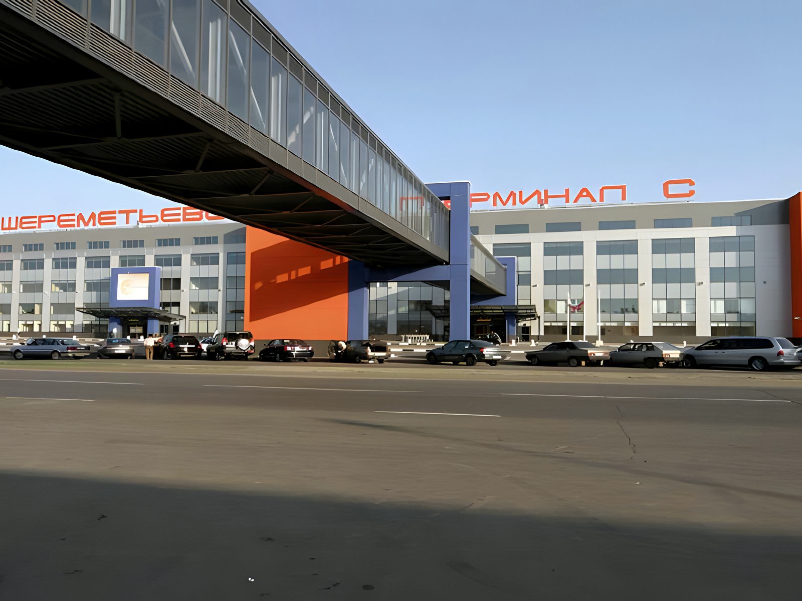 Terminal frontage under an elevated walkway, cars on forecourt