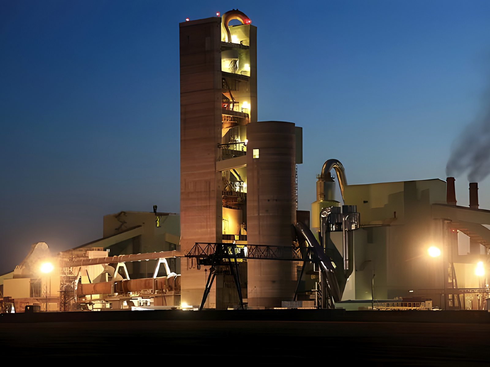 Cement plant silos and kiln house lit at twilight