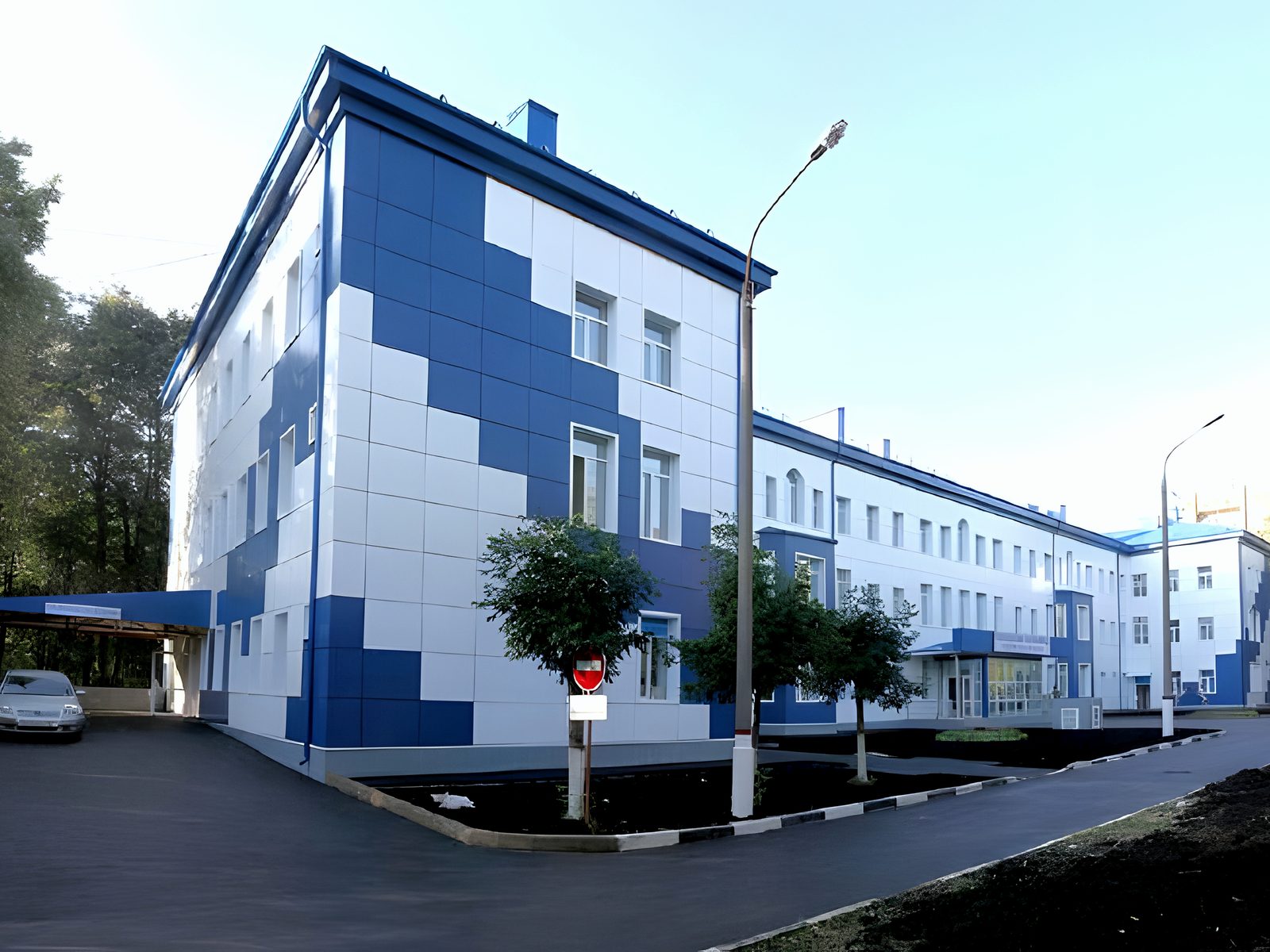 Blue-and-white hospital block on its corner, trees alongside