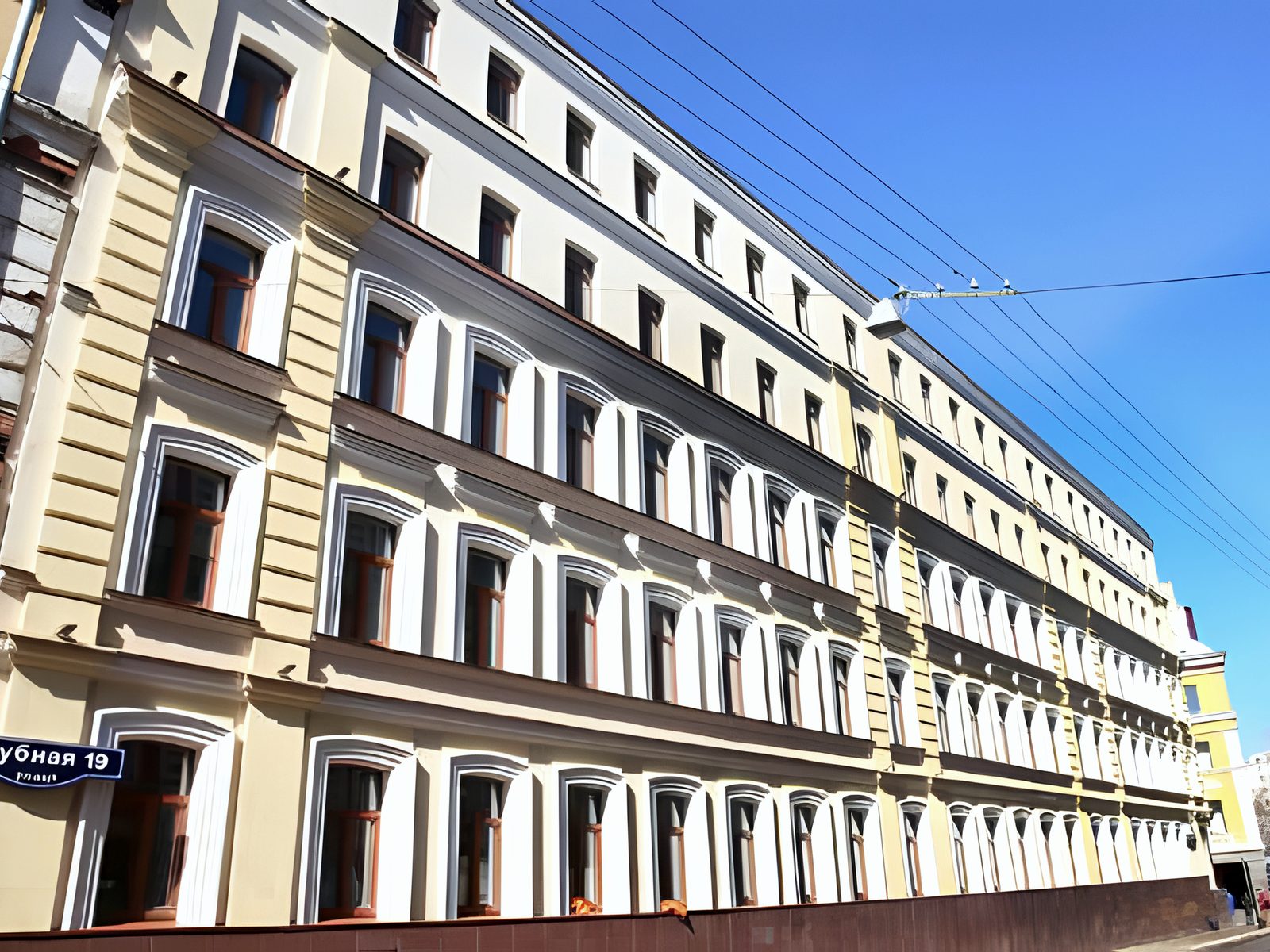 Restored classical facade in raking sun, street name plate