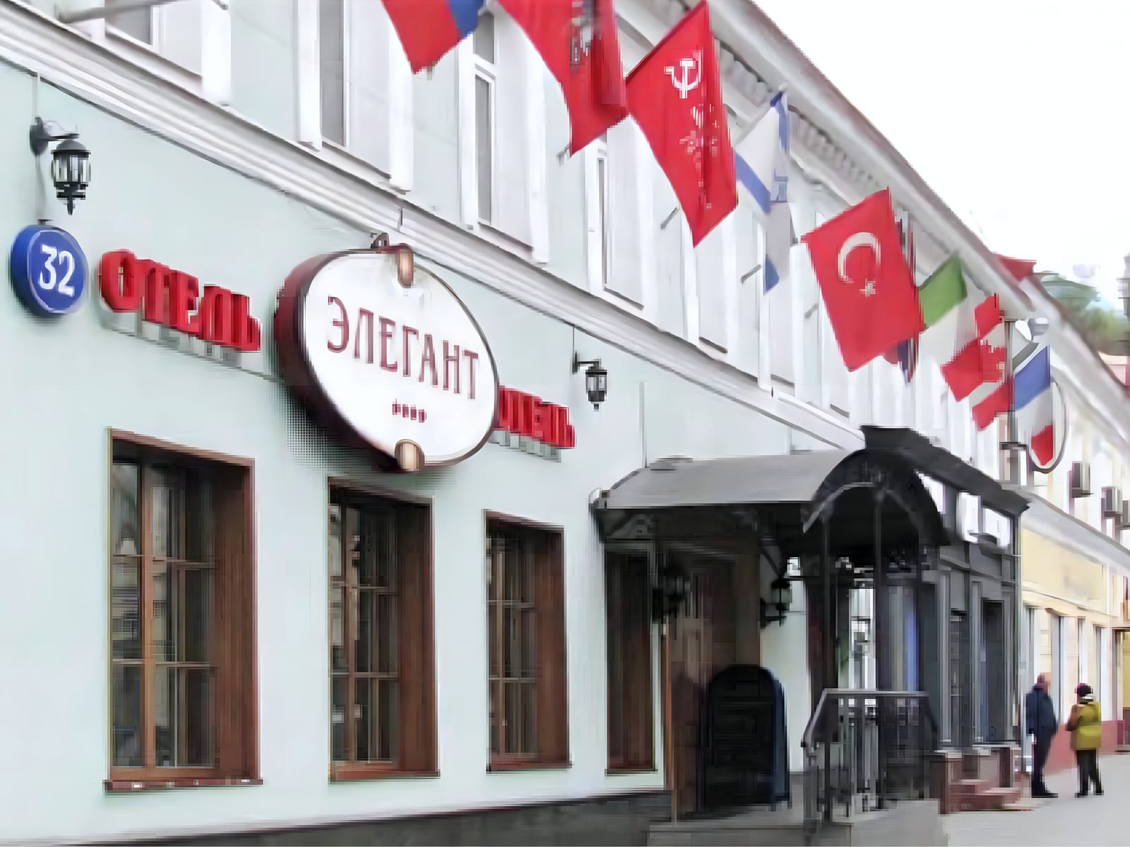 Street facade of the Boutique Hotel Elegant on Pokrovka Street, Moscow, with its ОТЕЛЬ ЭЛЕГАНТ sign, house number 32 and a row of flags