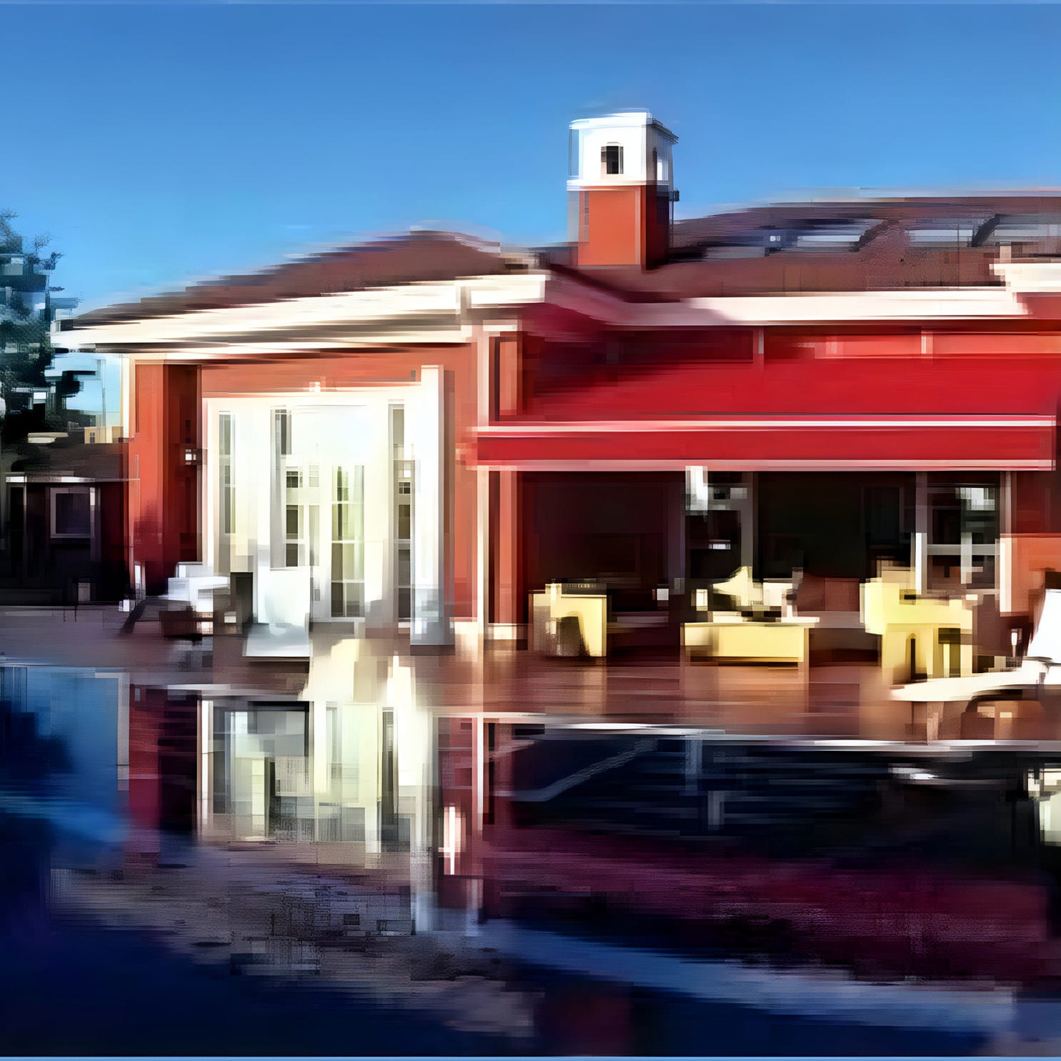 Red villa with awninged terrace reflected in a swimming pool