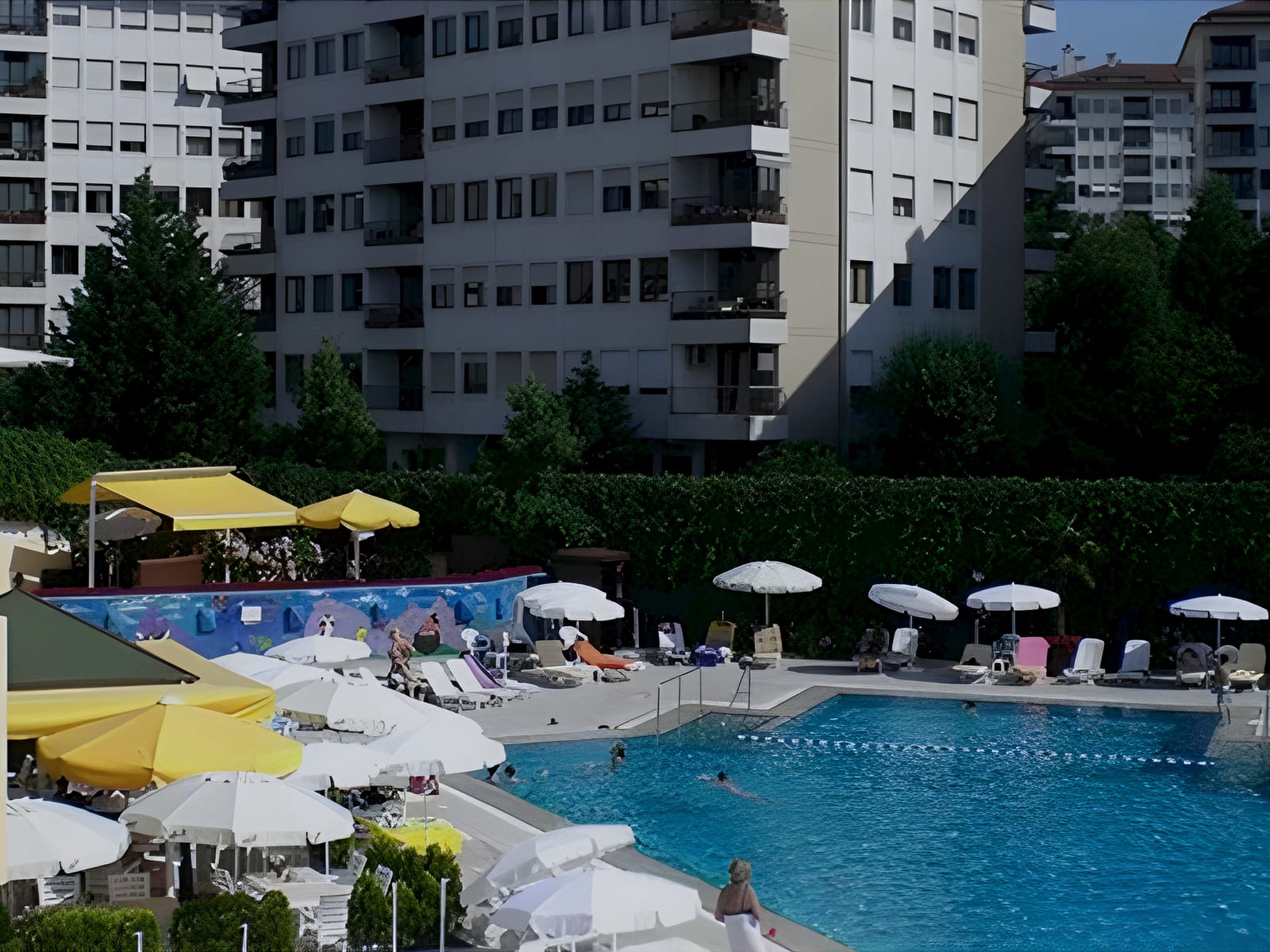 Outdoor pool with white and yellow umbrellas below the apartment blocks at Alkent, Istanbul, Turkey