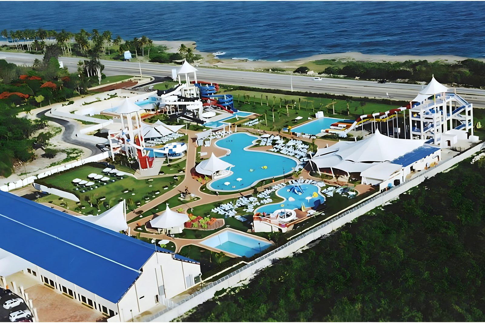 Aerial of seaside water park: pools, slides, tensile canopies