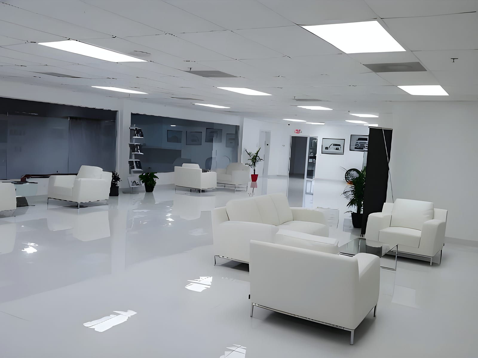Finished car-showroom lounge: white epoxy floor, white leather seating around glass tables, LED ceiling panels and framed car prints