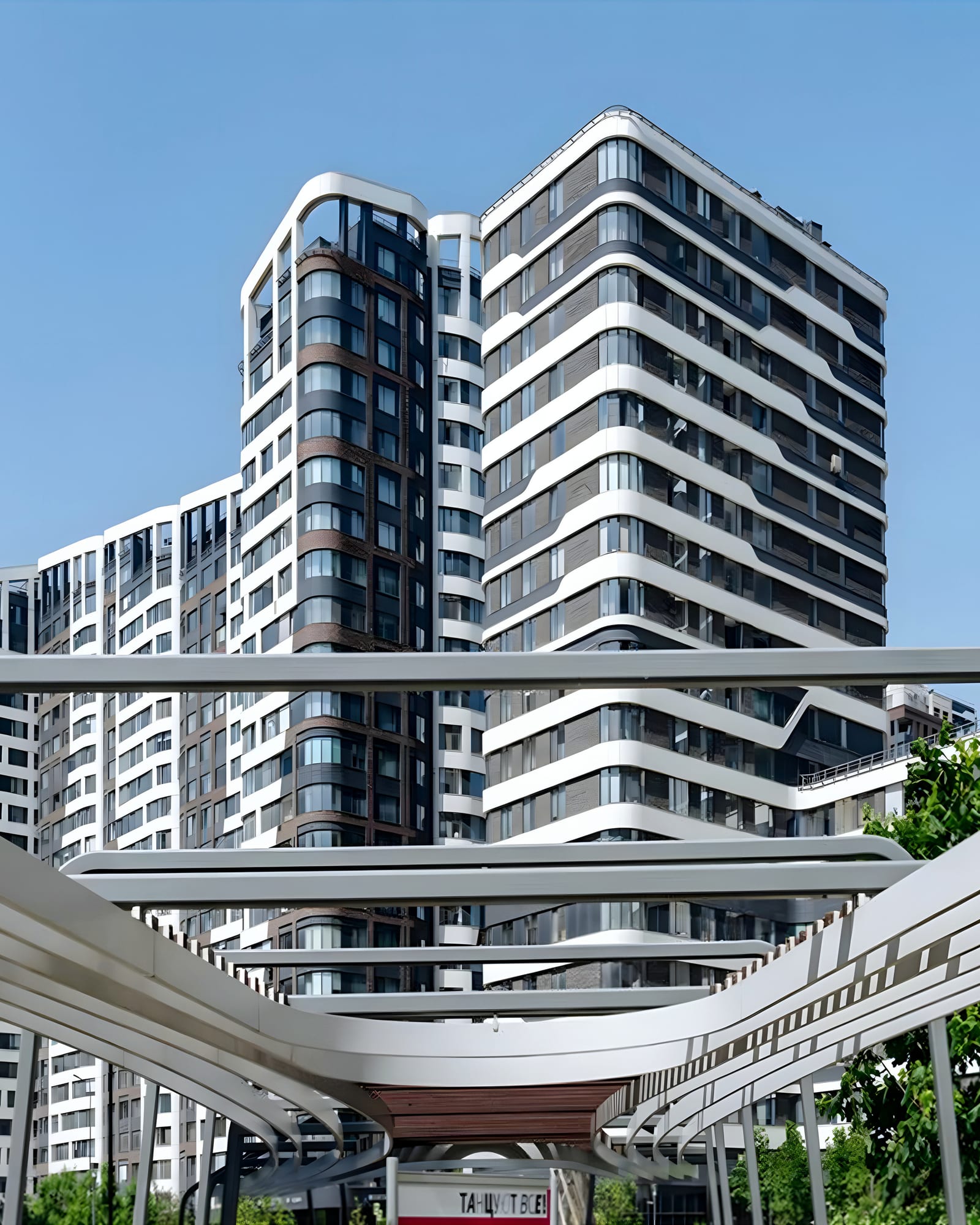Curved-balcony residential towers behind a white steel canopy