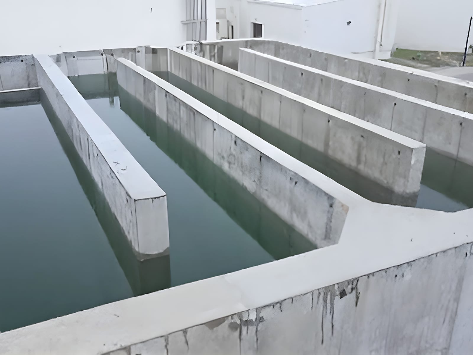Concrete foundation bays holding green water on the cleared hotel site in Miami Beach, Florida